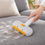 Yellow Duck pet hair remover brush used on a grey sofa