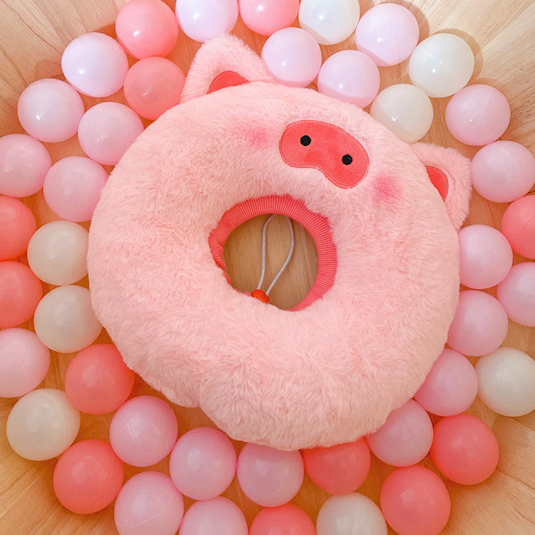 Pink pig plush pet neck warmer shown on colorful balls