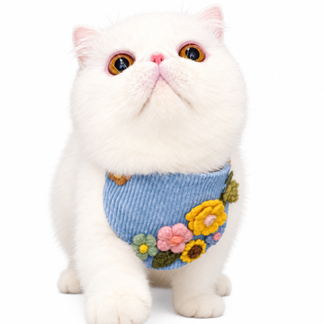 White cat wearing a blue floral pet bib scarf in a product scene