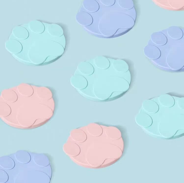 Pastel paw-shaped silicone cat food lids arranged on a blue background
